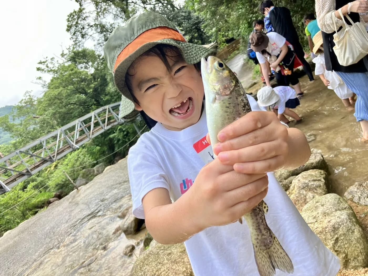 デイキャンプで自分でつかまえた魚を、満面の笑顔で掲げるこども
