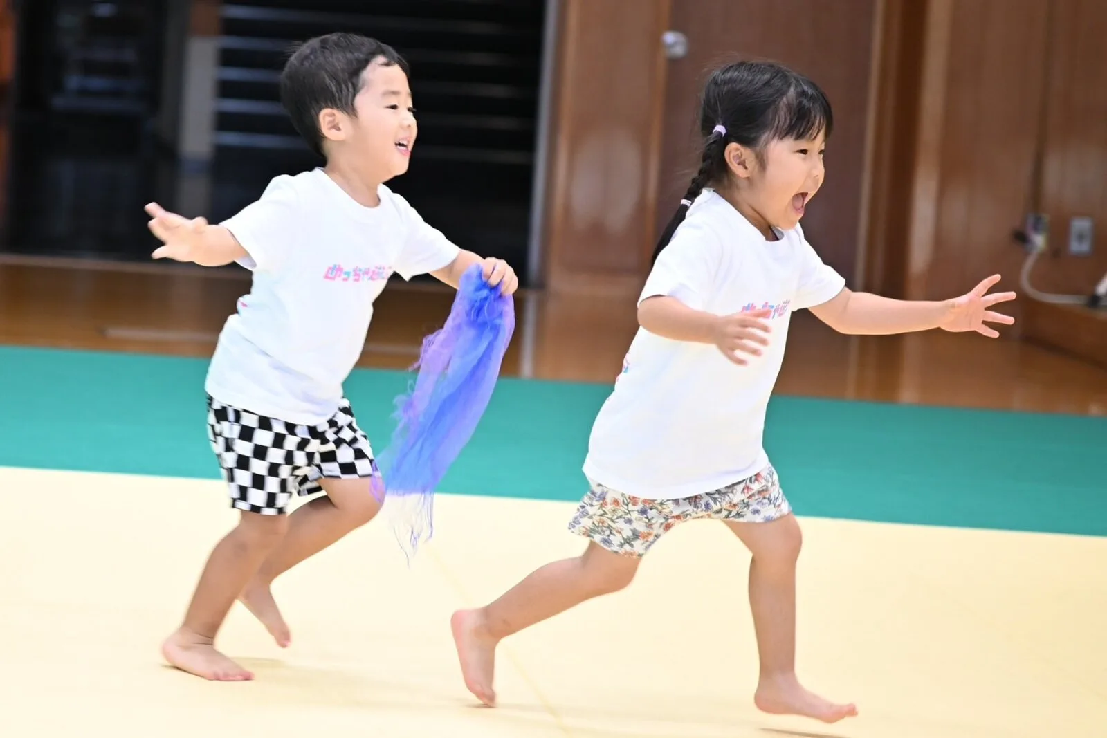 スカーフを持って笑顔で駆け回るこどもたち